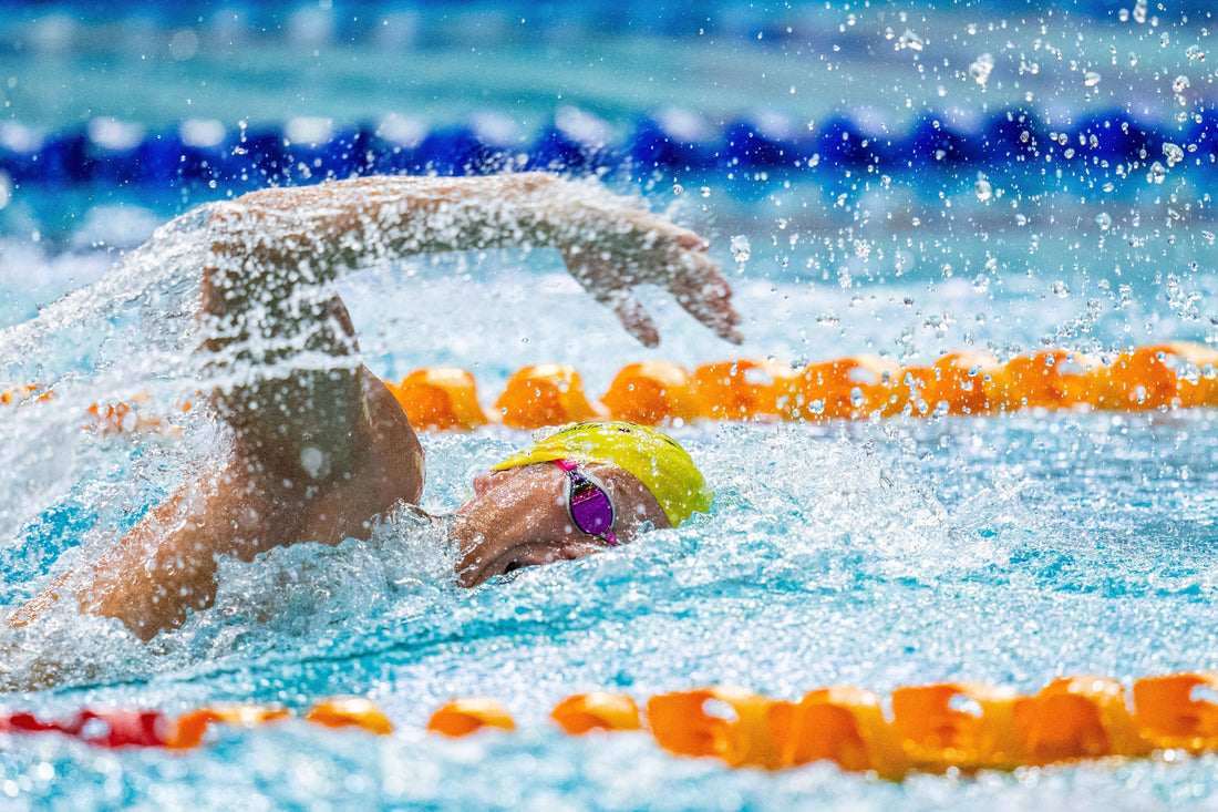 Swimmer using swim paddles during training session in pool