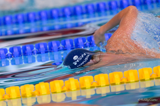 Swimmer training in pool with proper technique, demonstrating efficient stroke mechanics and hand placement